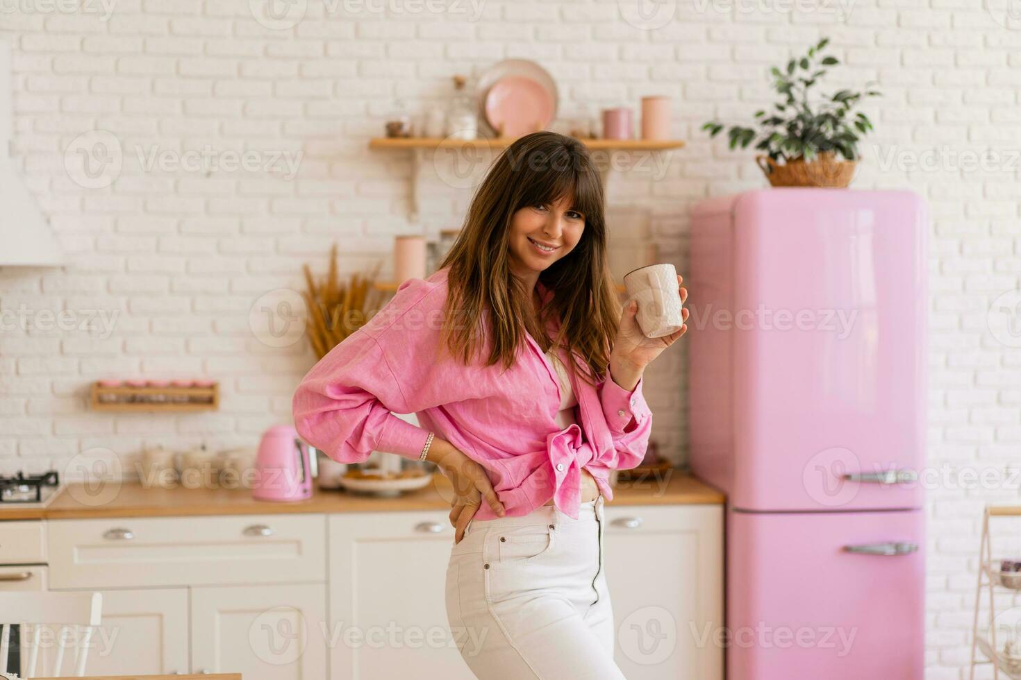 Stylish brunette woman enjoing cozy morning with cup of tea in light modern kitchen. photo