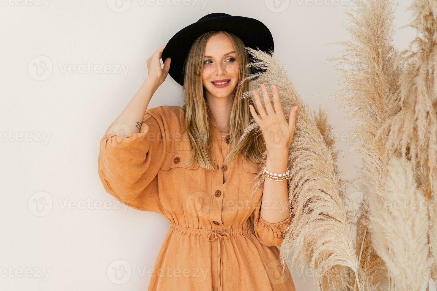 Stylish woman in summer outfit  posing  over white background in studio with pampas grass decor. Wearing linen dress. photo