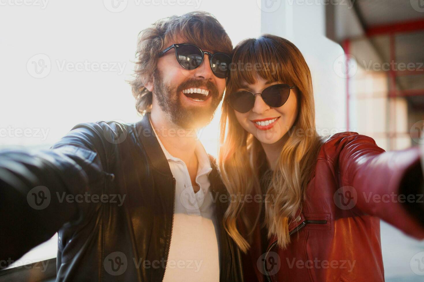 Happy beautiful stylish couple of love making self portrait by camera, walking in modern city. Perfect smile, leather jacket.  Fashionable outfit. photo