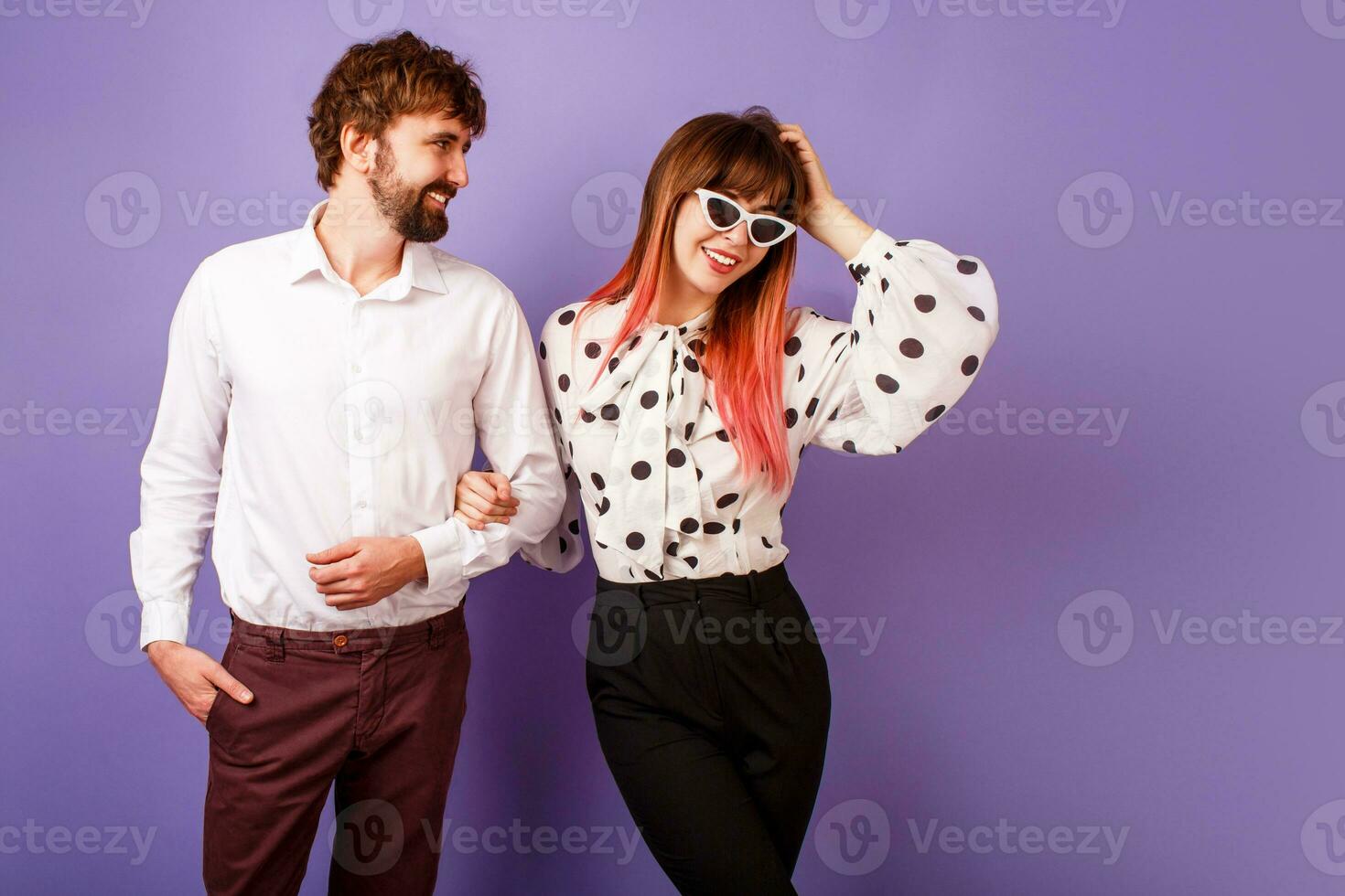 Fashionable couple in love posing in studio on purple background. photo