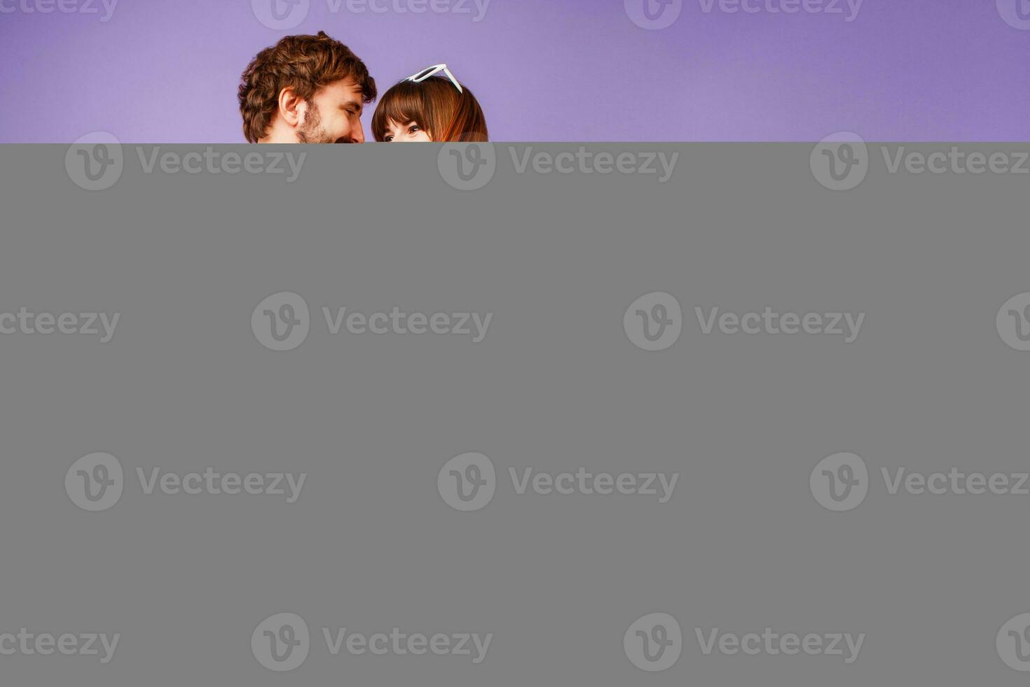 Elegant  couple in love hugging and looking on camera. Handsome  man with beard and his pretty woman with pink hairs in stylish retro outfit posing on purple background in studio. photo