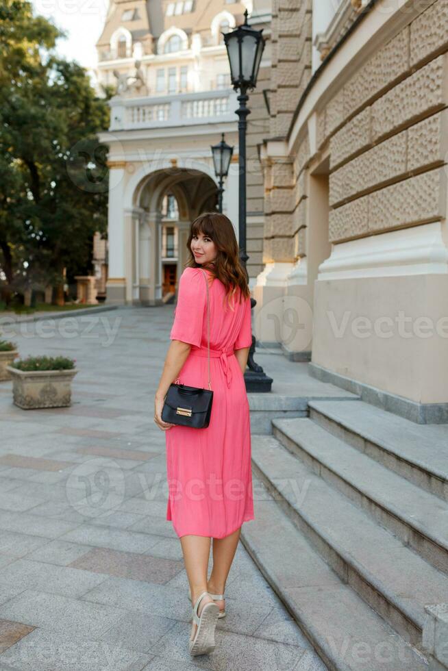 bonito mujer en rosado vestir posando en el calle. foto