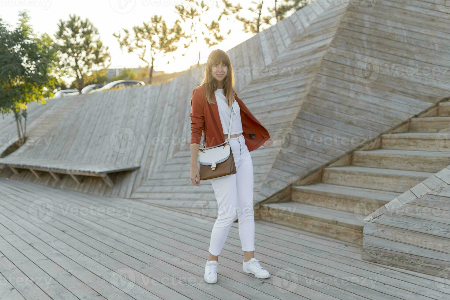 Happy   stylish female student posing in modern park , wesring white jeans, jacket and t-shirt.  Full lenght. photo