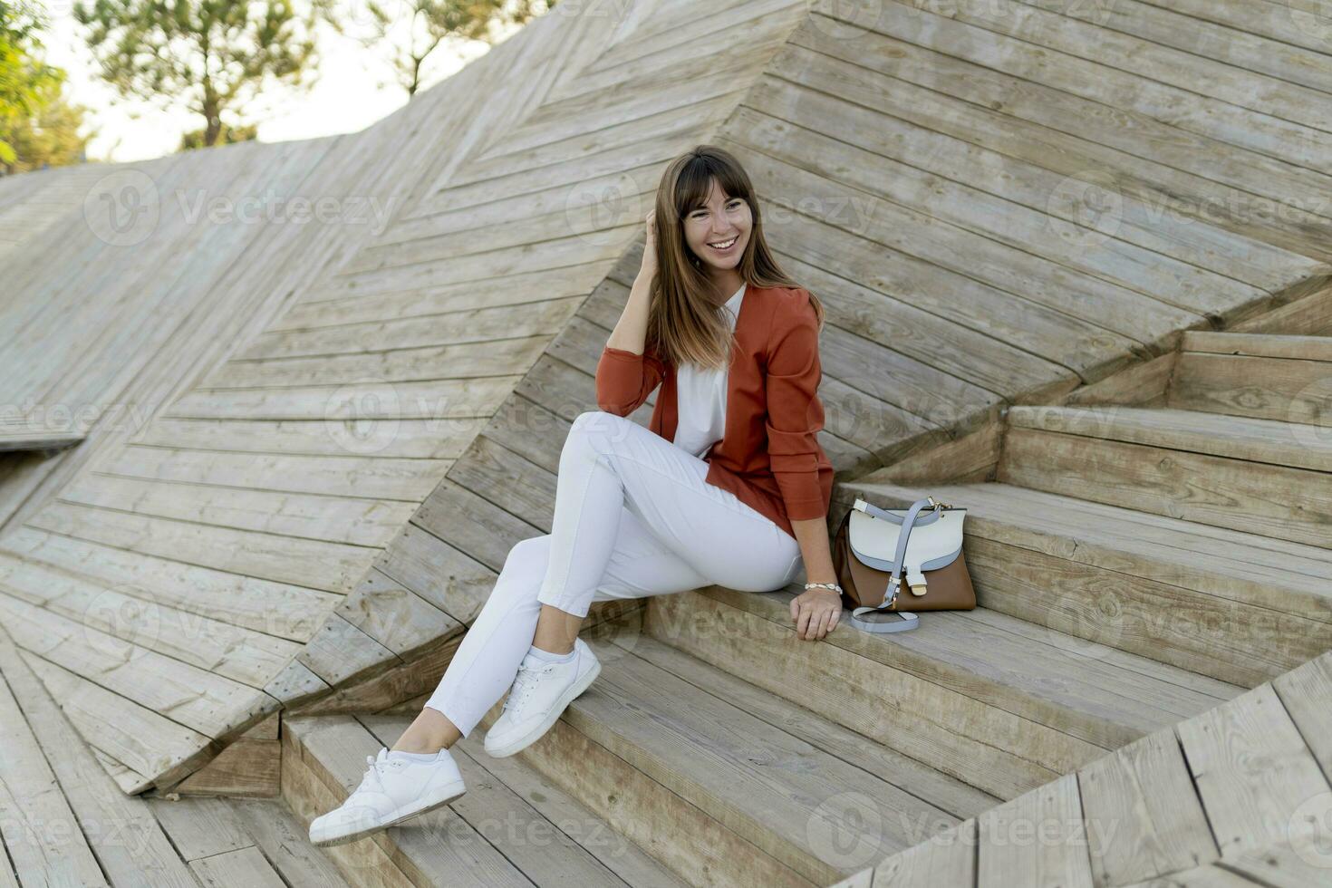 Happy   stylish female student posing in modern park , wesring white jeans, jacket and t-shirt. photo