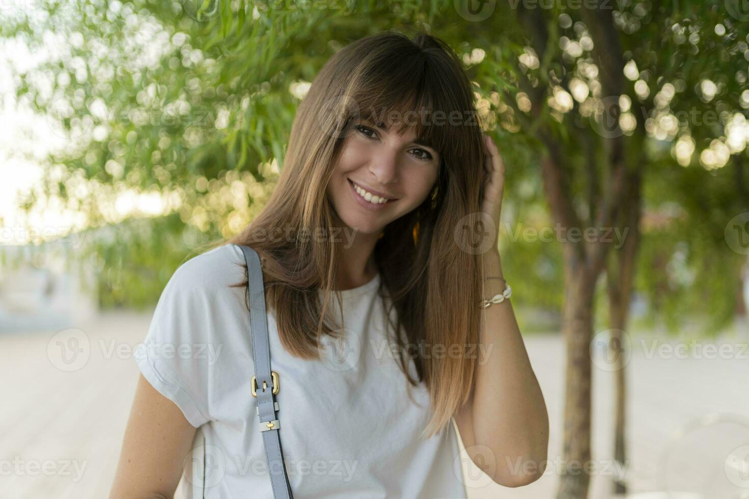 Close up portrait of laughing european female in white t-shirt posing in the park. photo