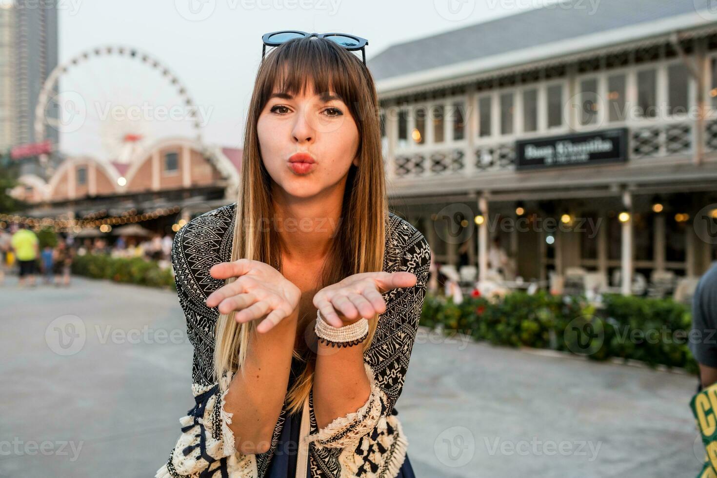 Young travel woman send kiss , having great time  on riverfront of Bangkok , ferris wheel  and  restaurants background. photo