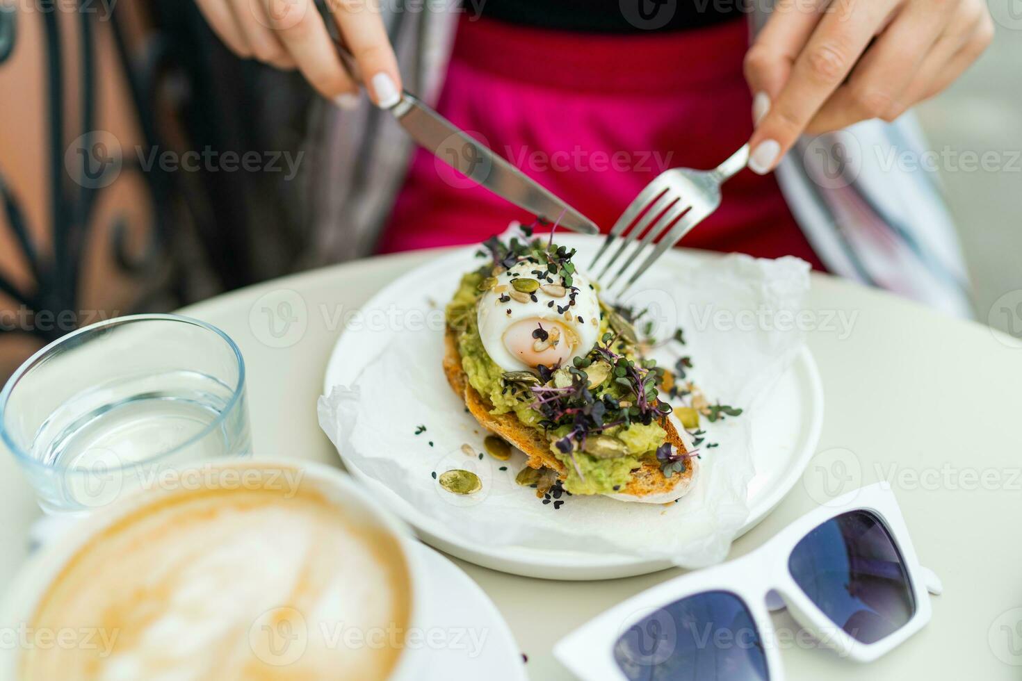 Woman enjoing avocado toast in cafe during breackfast. photo