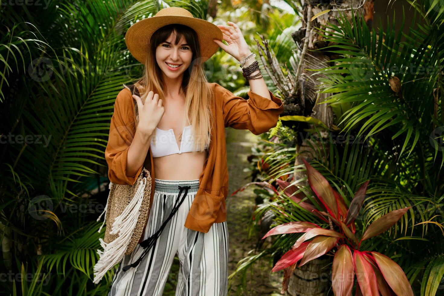 Well-dressed  woman  in  perfect mood playfully posing in  tropical garden.  Bali holidays.  Boho accessories. photo