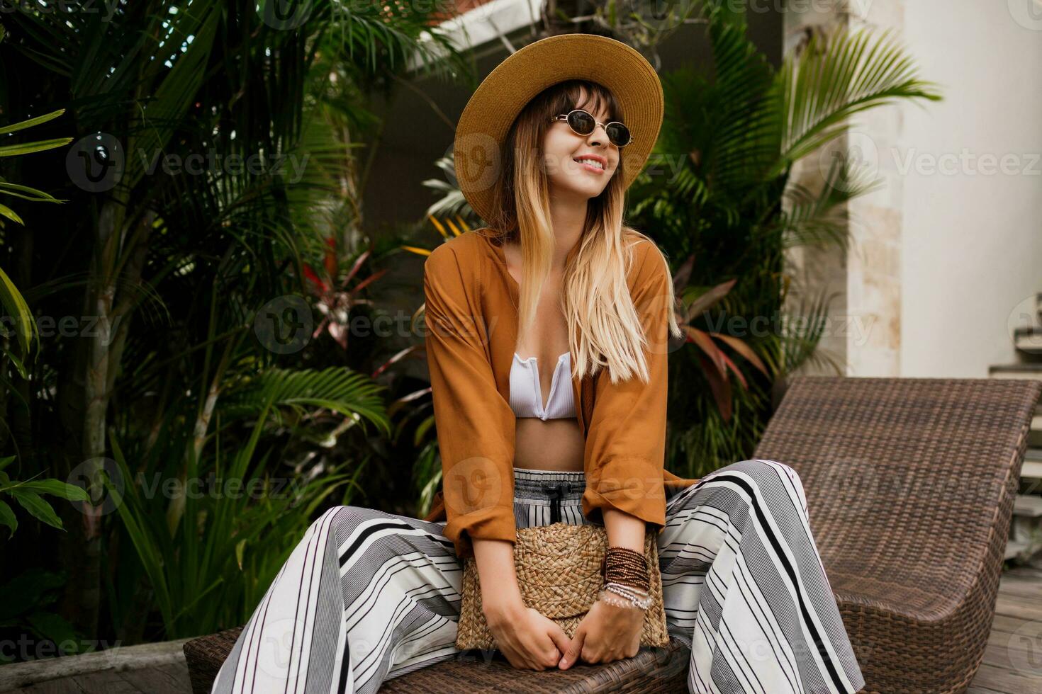 Vacation time in Asia. Fashionable woman resting  in  resort, chilling near pool. Wearing bohemian summer accessories . photo