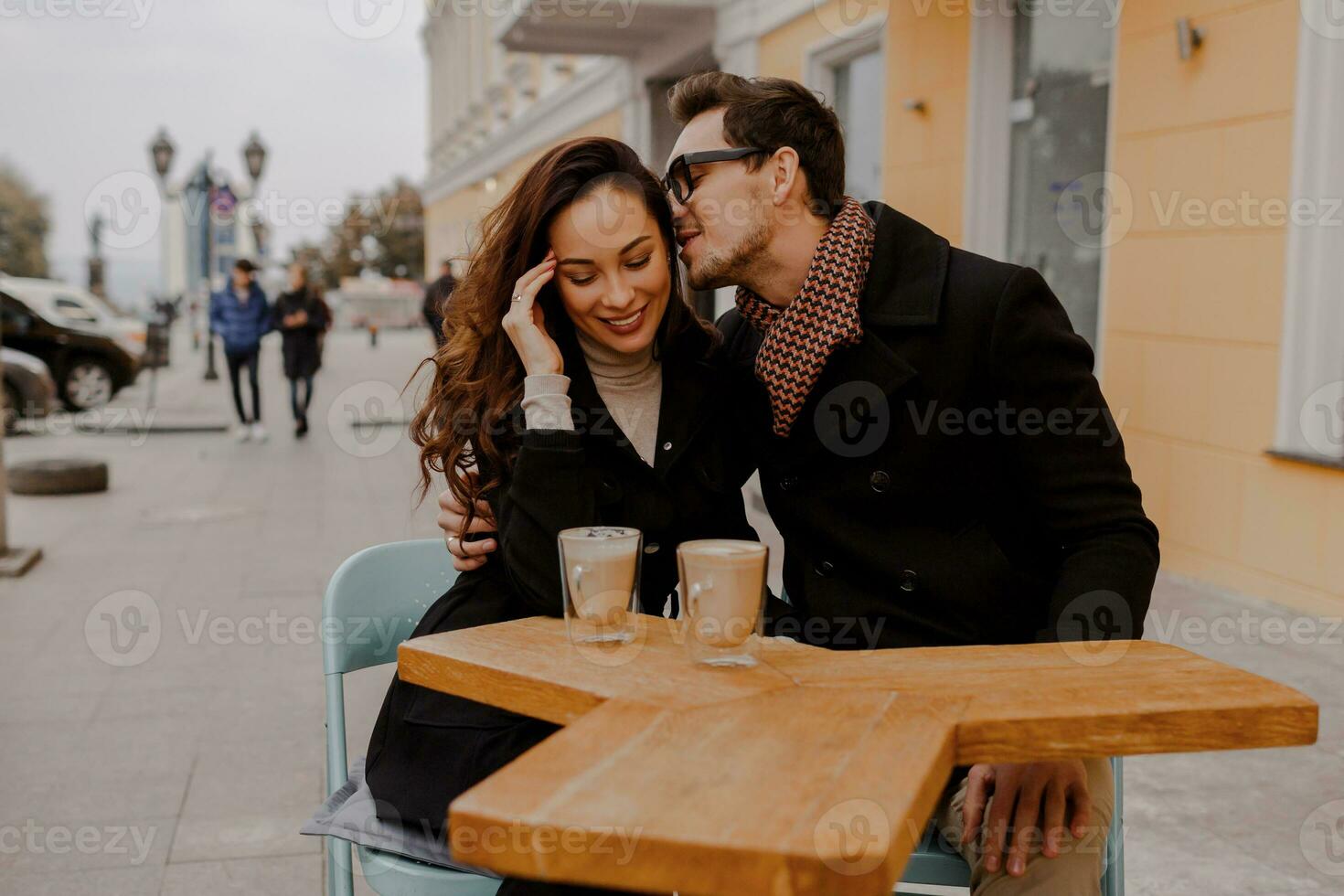 Fashionable couple in love sitting in street cafe  and drinking hot coffee while traveling in Europe. photo