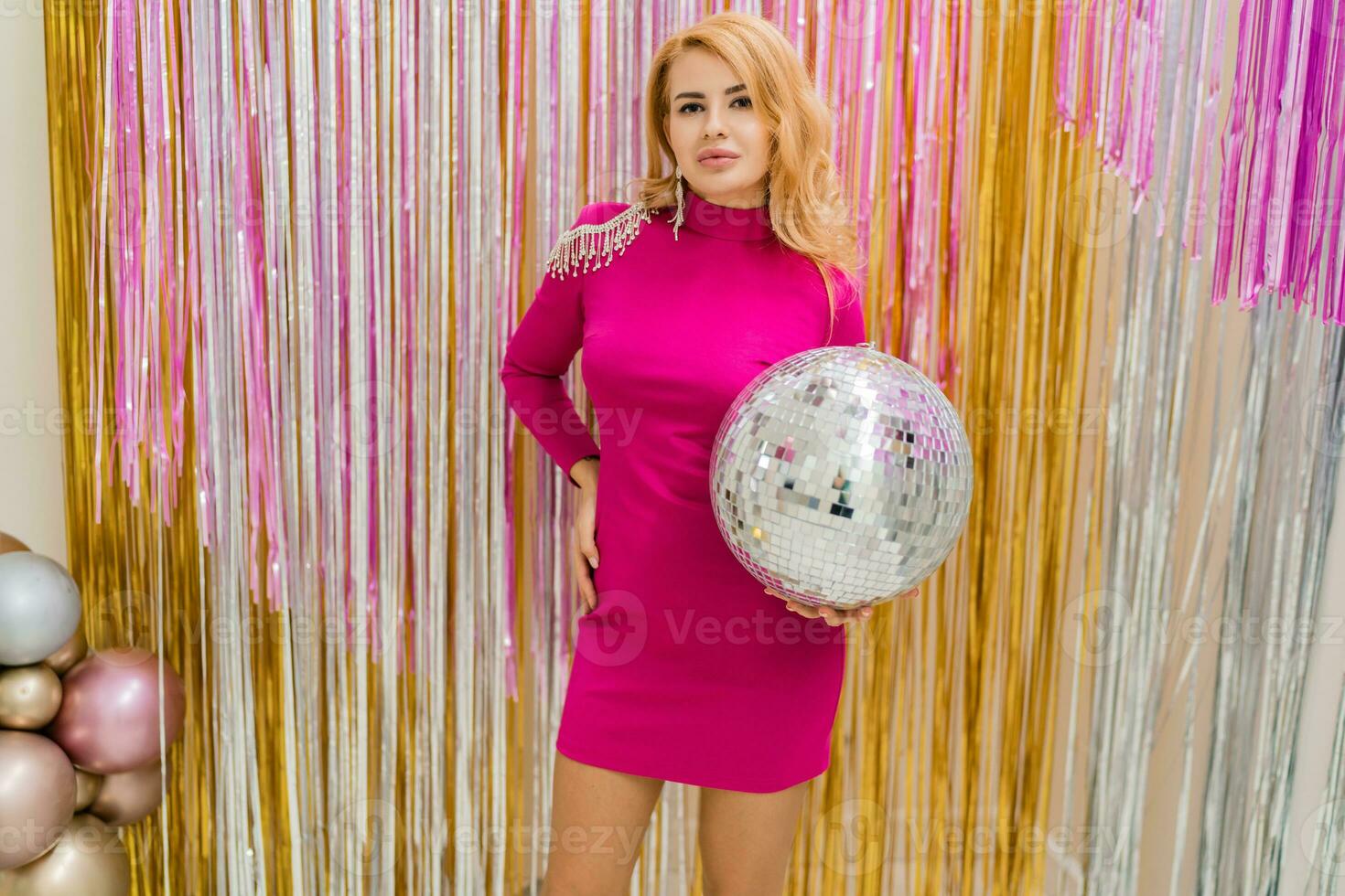 Studio photo of shiny blond woman in sexy pink dress. Perfect wavy hairs. New year  party.