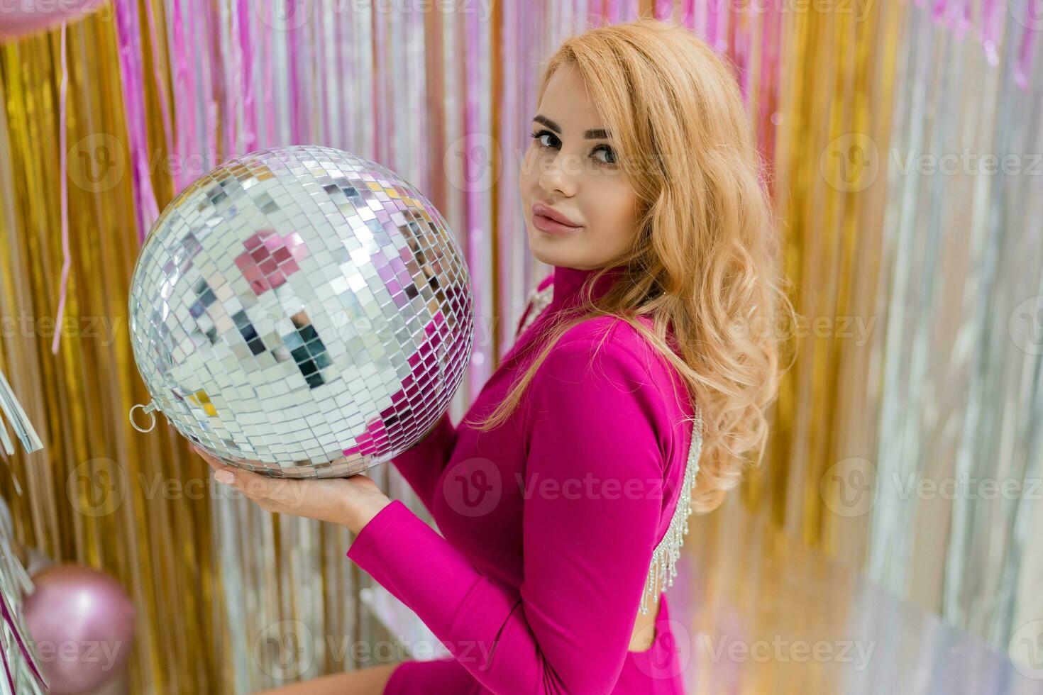 Studio photo of shiny blond woman in sexy pink dress. Perfect wavy hairs. New year  party.