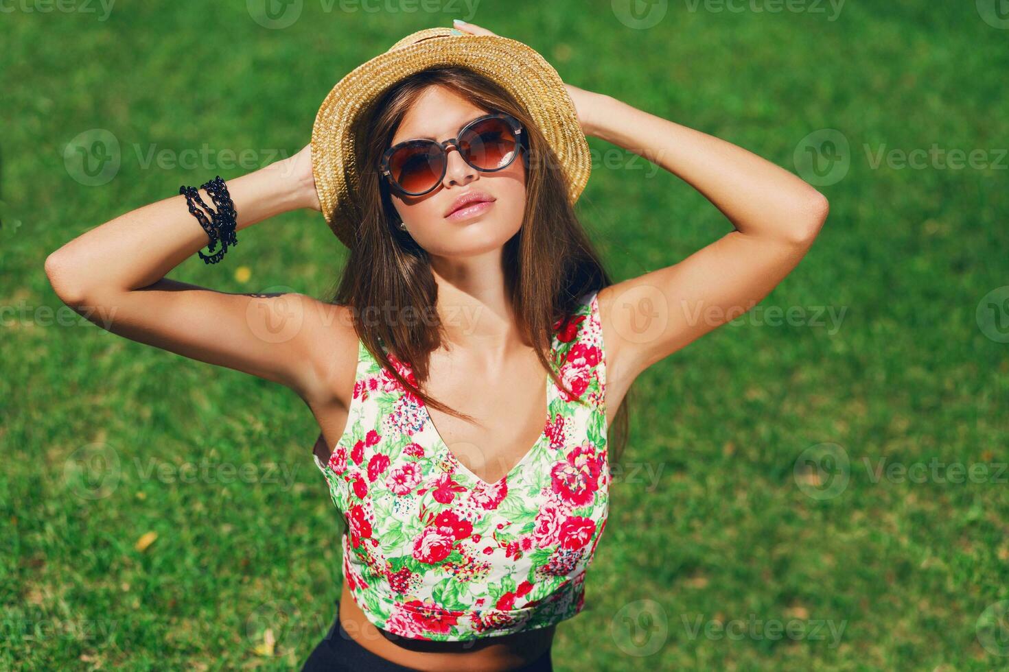 Close up outdoor portrait of seductive young  woman  smiling , sitting on green  fresh grass in sunny spring park . Perfect tan skin.  Long slim legs. photo