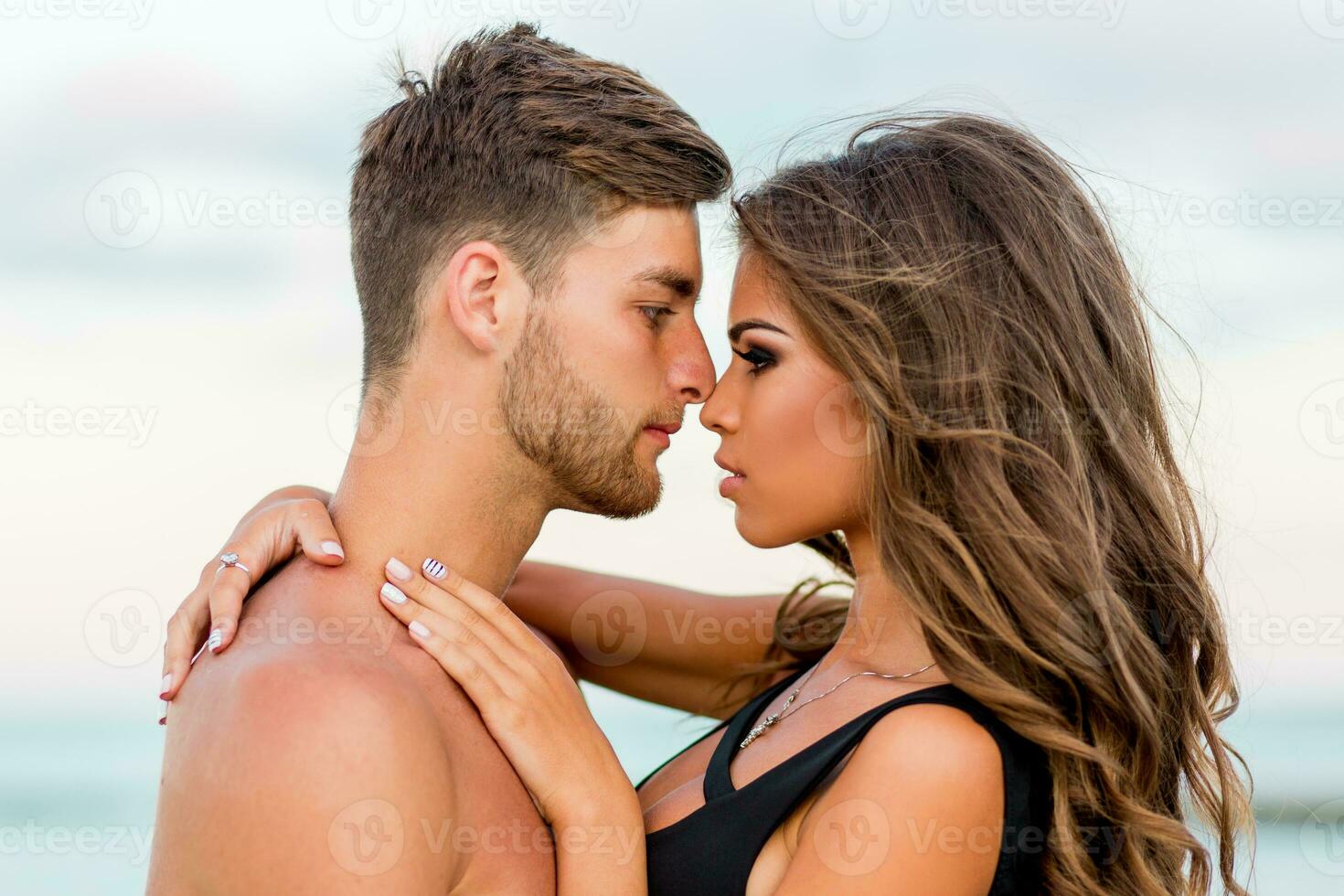 Outdoor close up fashion portrait of pretty sexy couple in love  hugs on  amazing tropical  beach, wearing stylish swimwear. photo