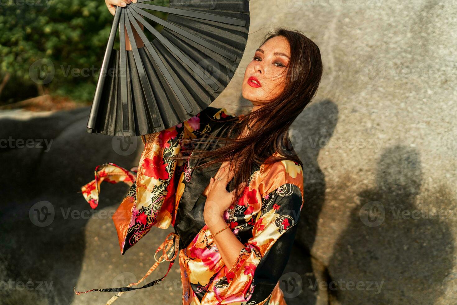 seductor mujer en elegante kimono con grande ventilador y profesional hacer arriba posando exterior. foto