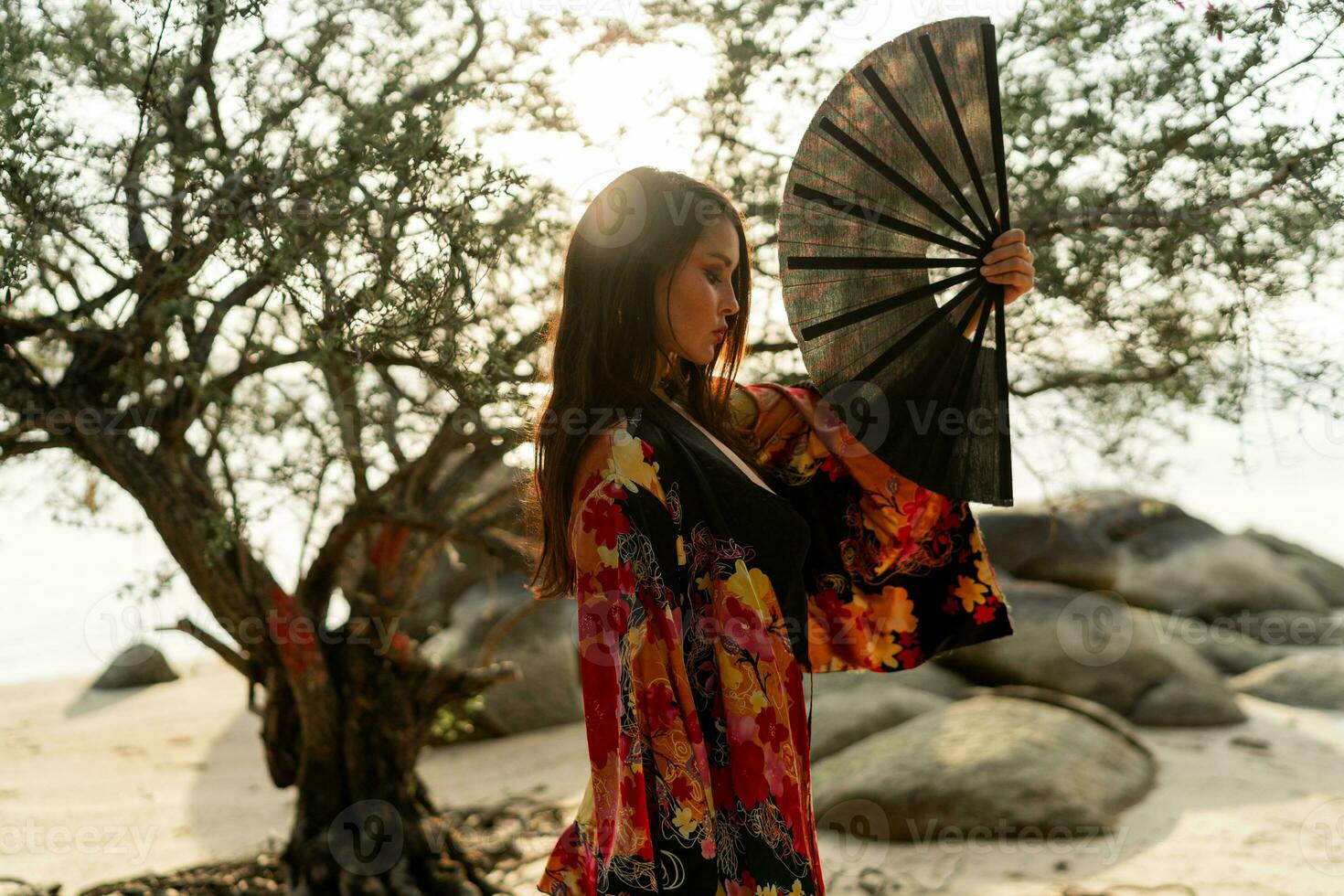 Elegant woman in stylish  kimono  with large fan and professional make up posing outdoor. photo