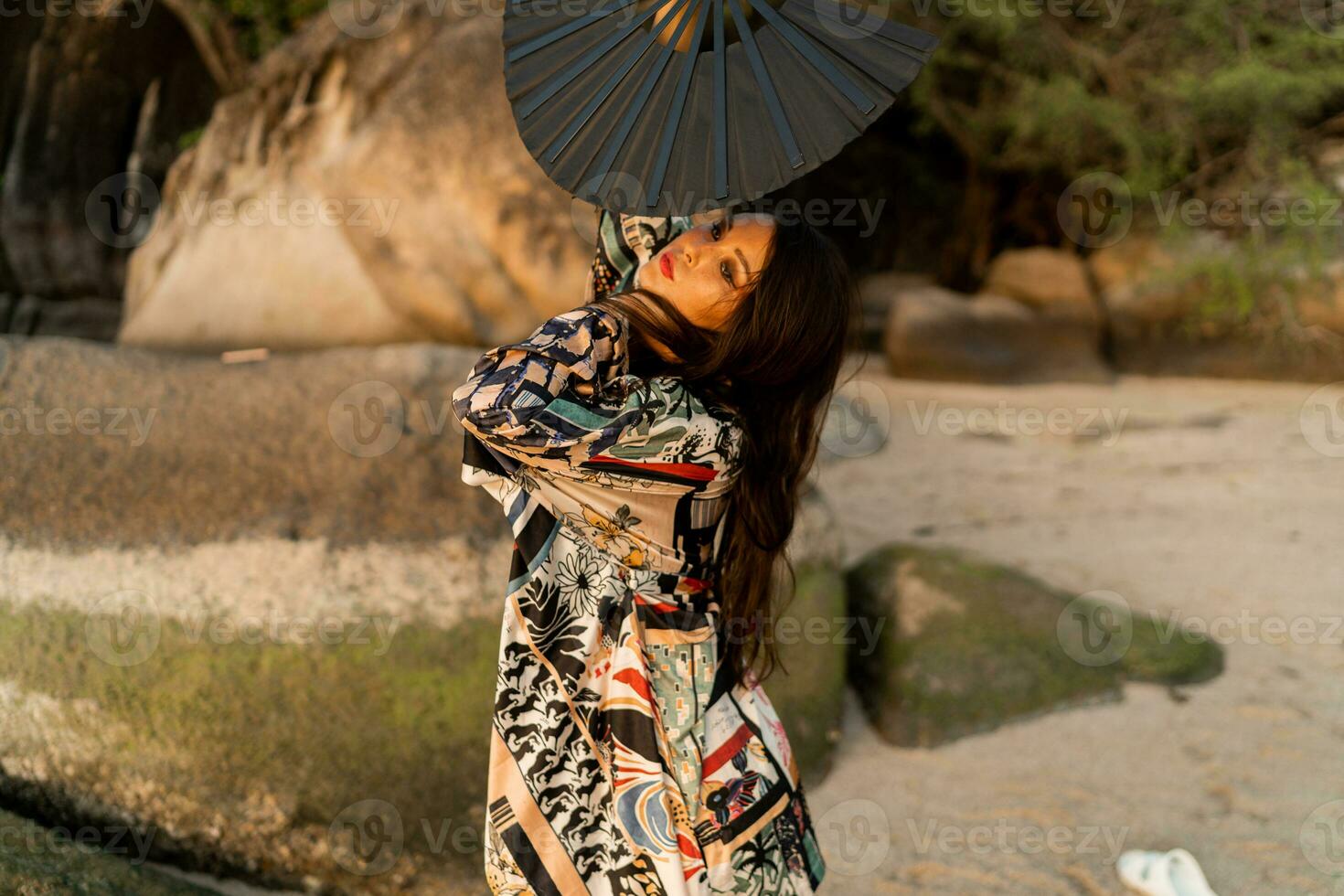 cerca arriba retrato de seductor japonés niña en elegante kimono con grande ventilador y profesional hacer arriba posando en el playa. foto