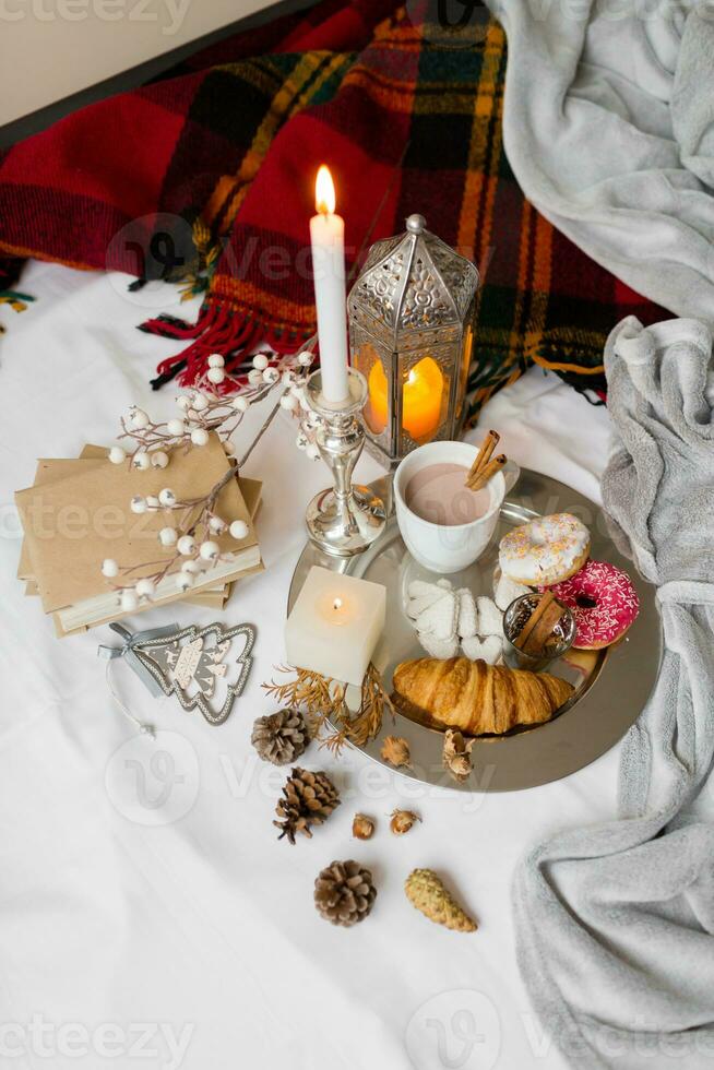 Still life with delicious Christmas gingerbread and cookies  breakfast on a tray in bed , donuts and croissants , cup of cacao or latte with cinnamon, ginger biscuits figure, Christmas candles. photo