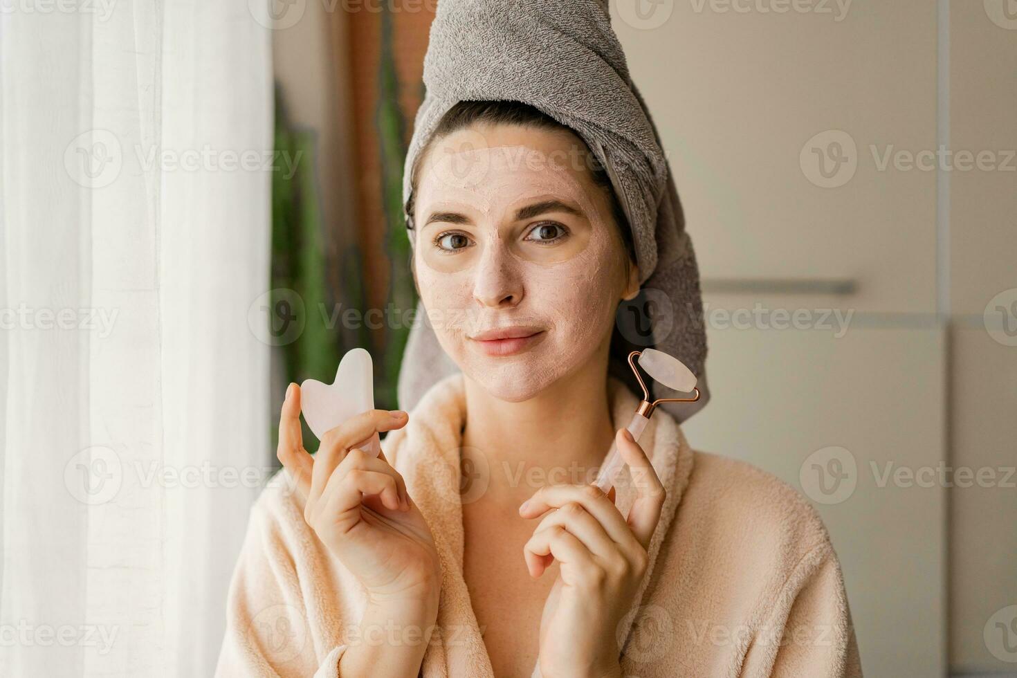 Skin care. Woman brushing clay mud mask to her face.  Posing on the modern livingroom.Cosmetic procedures. photo