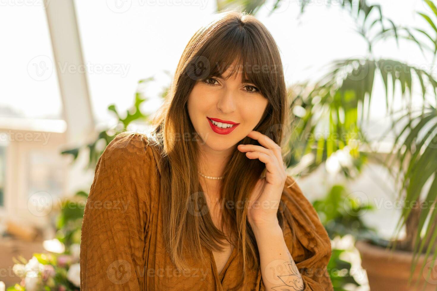 cerca arriba retrato de hermosa morena mujer posando en elegante bohemio vivo habitación con hogar plantas. foto