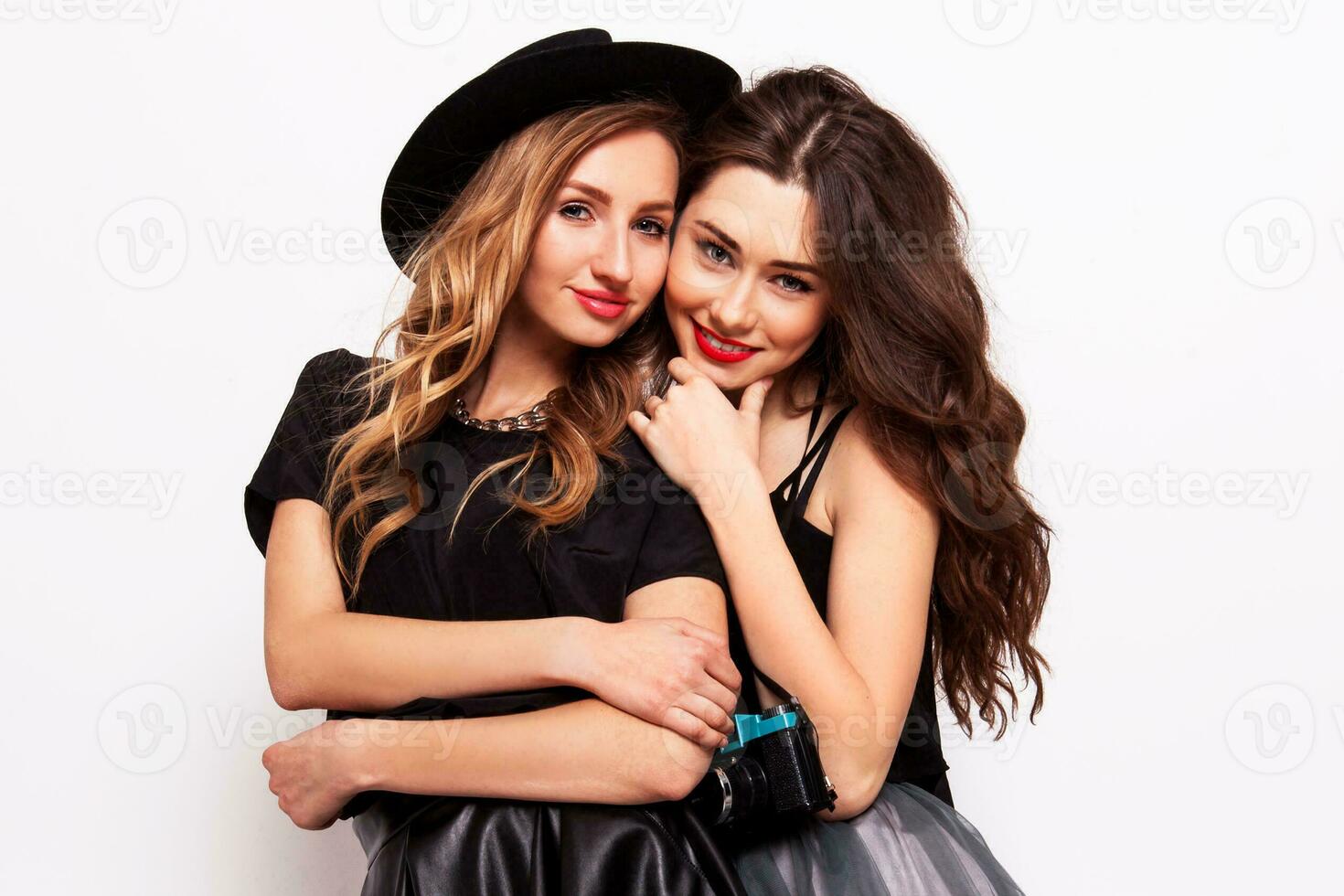 Two pretty stylish girls have fun and laughing. Best friends  in fall outfit posing in studio.Perfect wavy hairstyle. photo