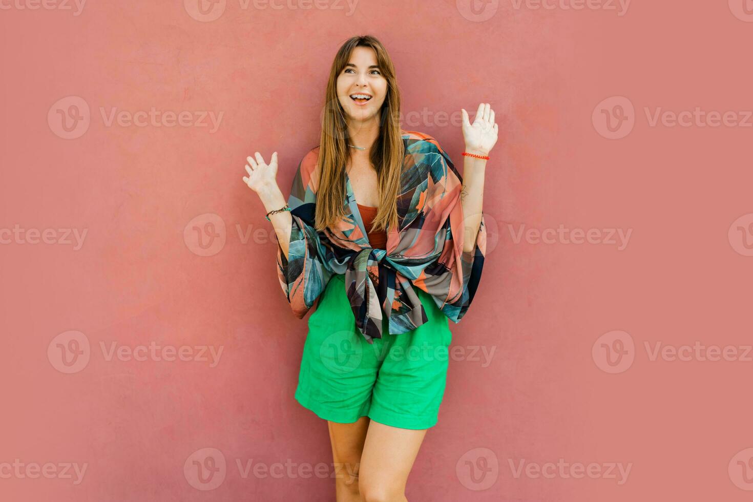 Woman with suprice face  in stylish boho clothes posing over pink background. Summer fashion trends. photo