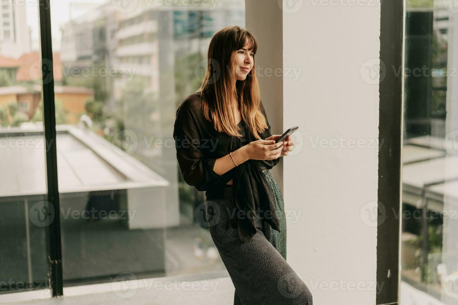 Stylish business woman in fashionable casual outfit  talking by mobyle phone  during work day in  modern business center. photo