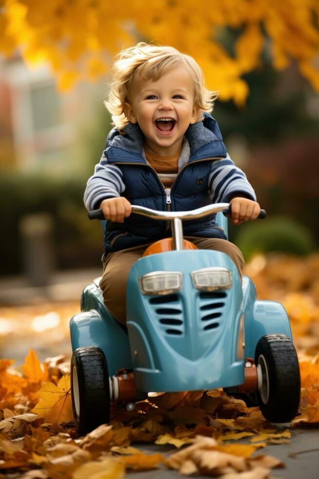 a young child riding a little car through the leaves in the fall photo