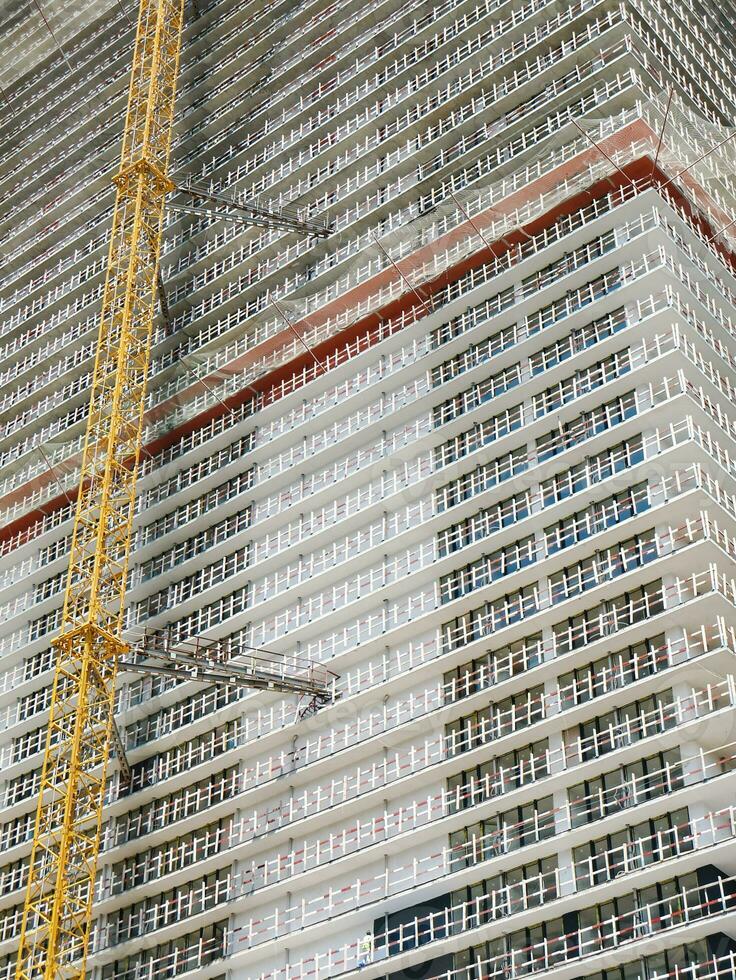 Modern unfinished skyscraper witha yellow lifting crane attached. photo