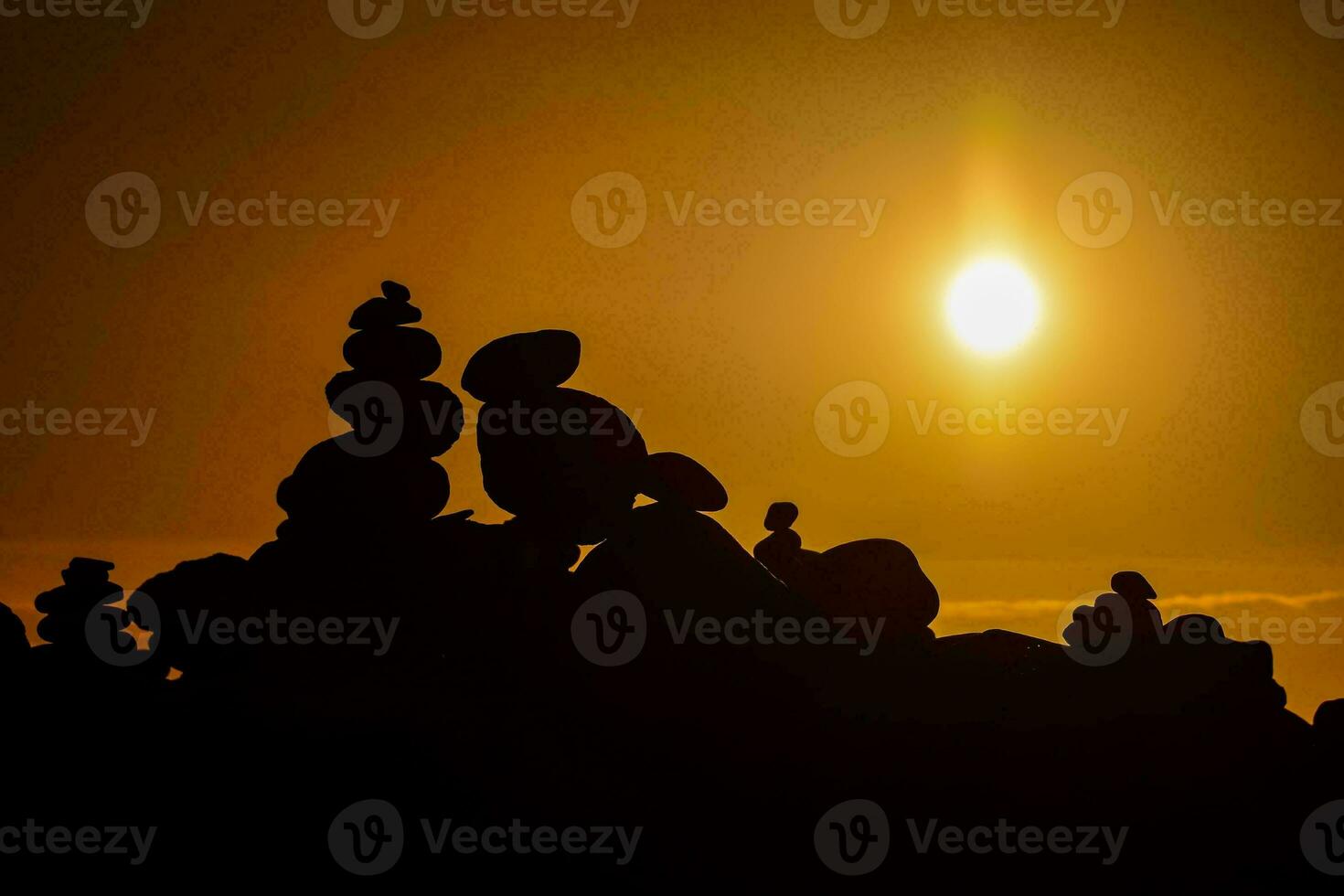 the sun is setting behind a pile of rocks photo