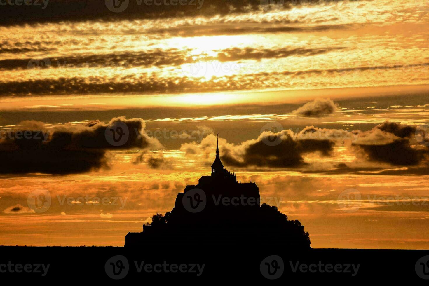 the sun sets behind the silhouette of a castle photo