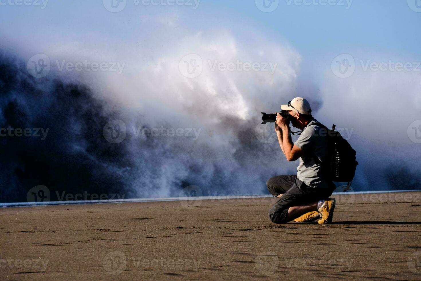 a man taking a photo of a wave crashing on the beach