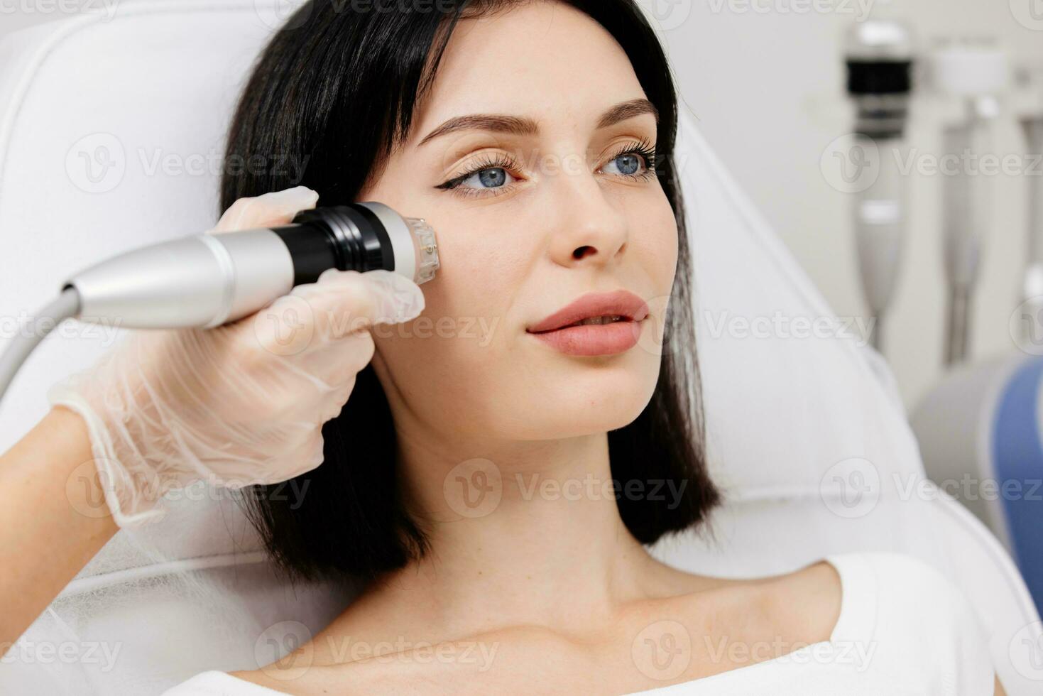 Woman undergoing a cosmetic procedure in a beauty salon. A woman undergoes fractional RF lifting against a light background. Advertising concept for clean and young facial skin. photo