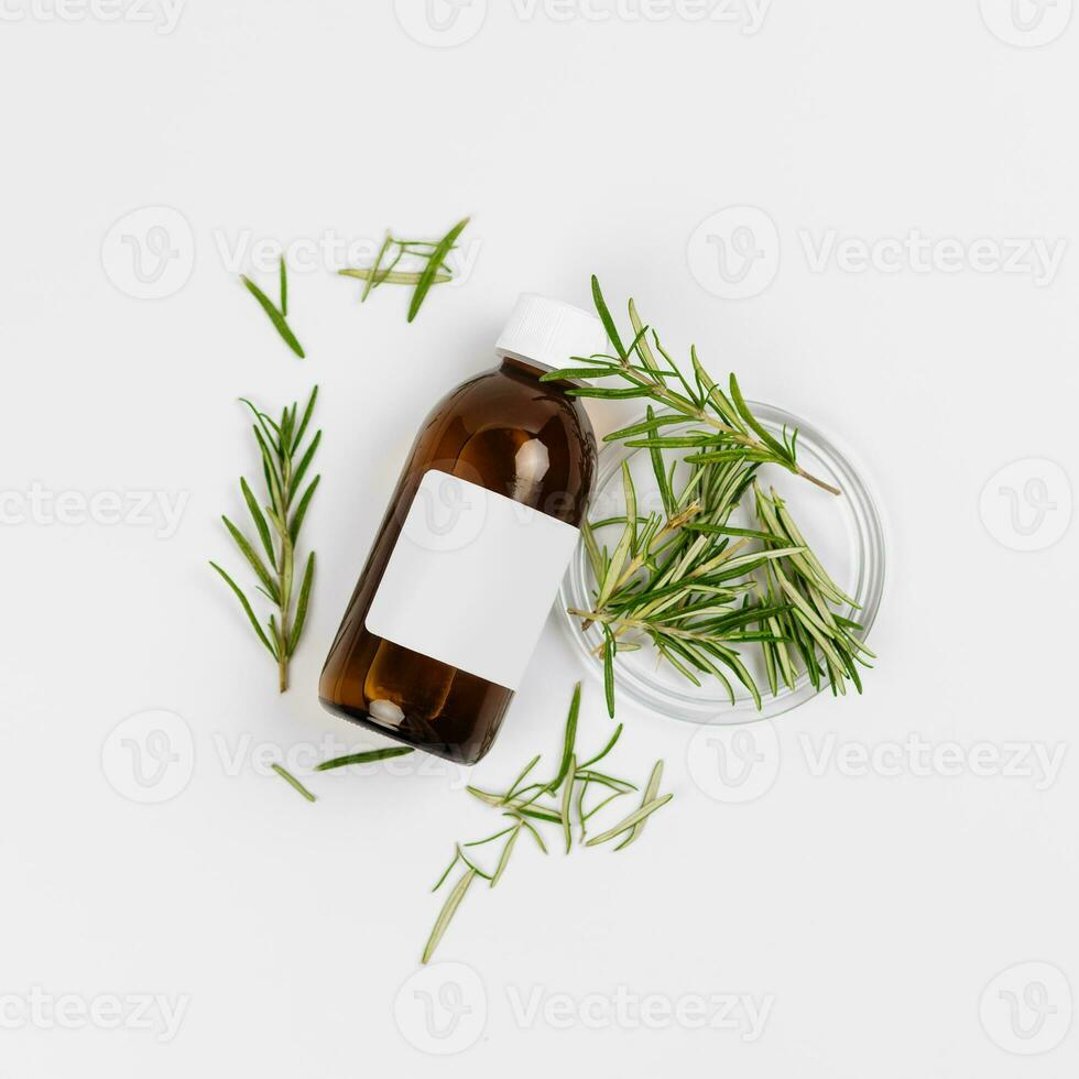 Cosmetic brown glass bottle and rosemary branches on white background. Background for cosmetic product branding, corporate identity and packaging inspiration. Mockup photo