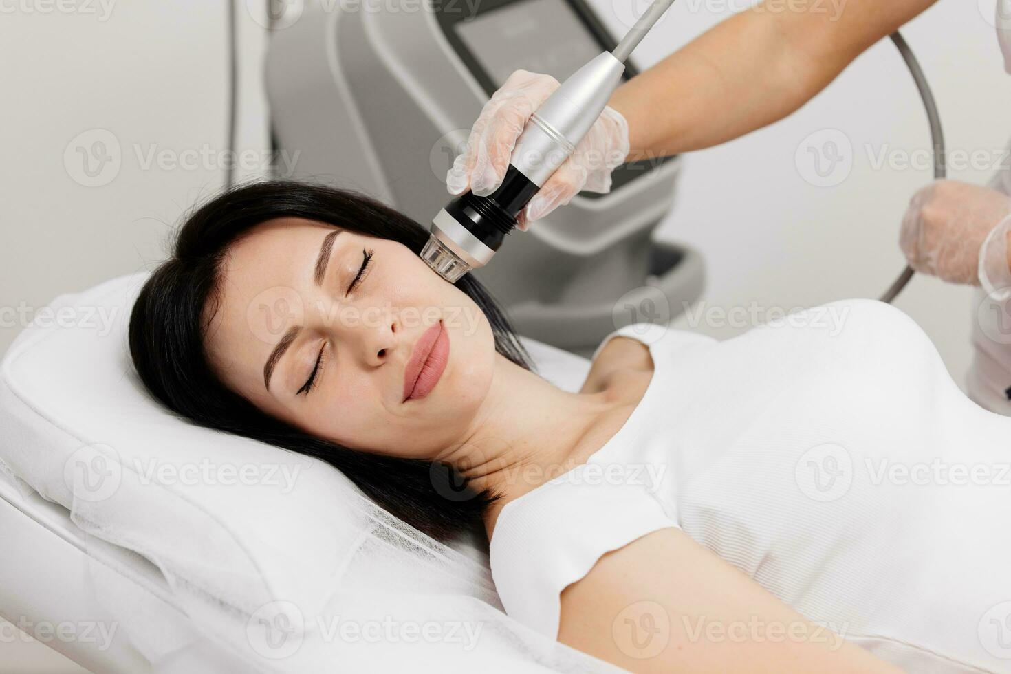 Woman undergoing a cosmetic procedure in a beauty salon. A woman undergoes fractional RF lifting against a light background. Advertising concept for clean and young facial skin. photo