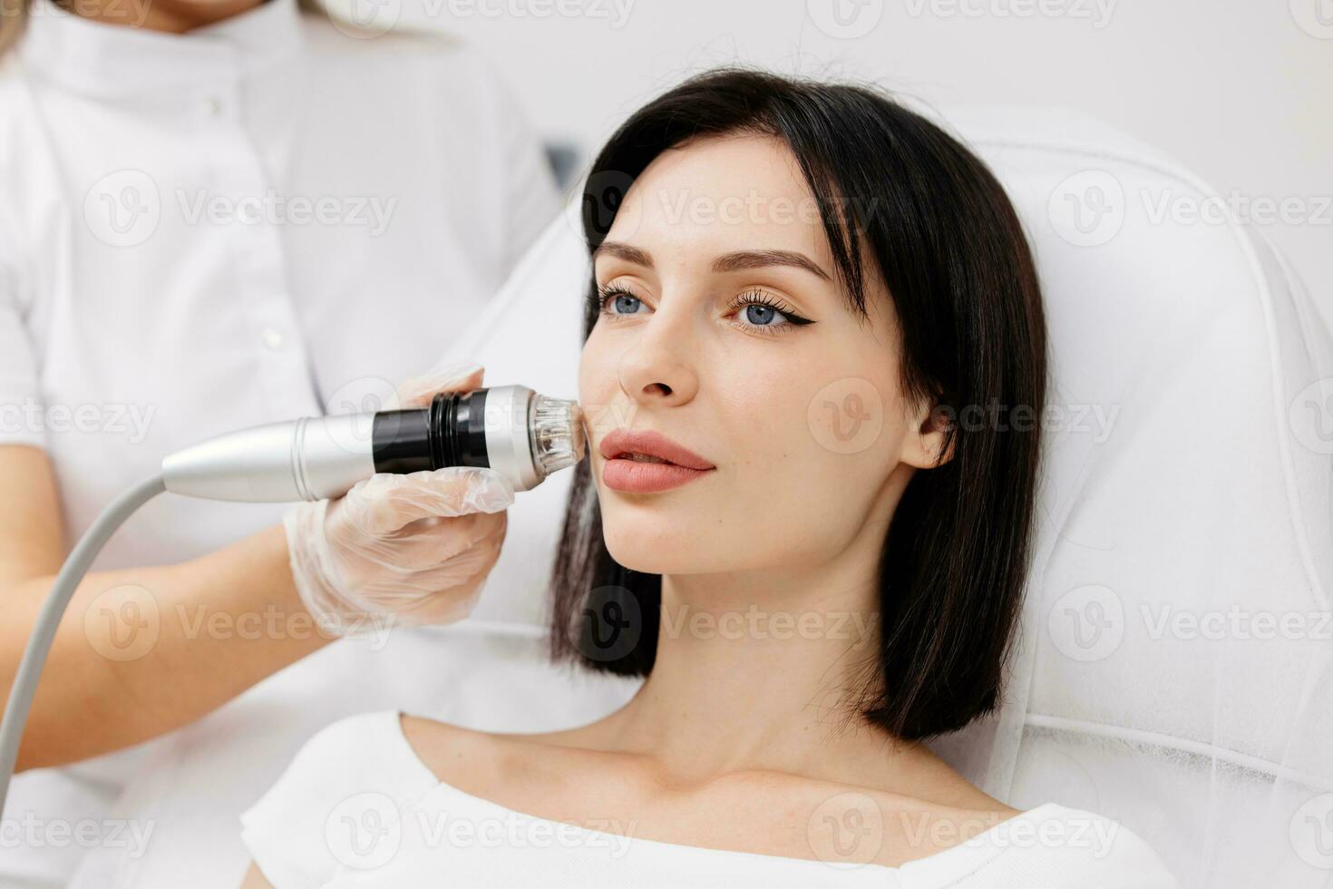 Woman undergoing a cosmetic procedure in a beauty salon. A woman undergoes fractional RF lifting against a light background. Advertising concept for clean and young facial skin. photo
