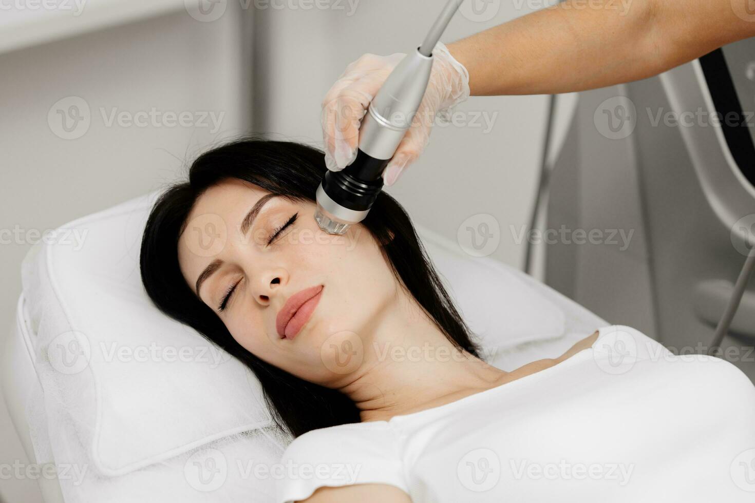 Woman undergoing a cosmetic procedure in a beauty salon. A woman undergoes fractional RF lifting against a light background. Advertising concept for clean and young facial skin. photo