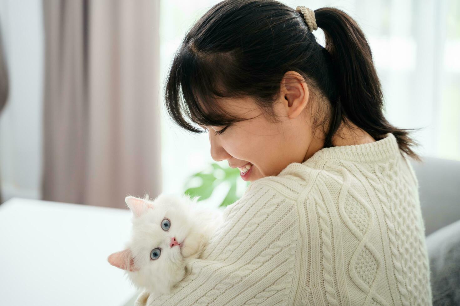 Happy Woman Playing with Cat in Cozy Living Room at Home. photo