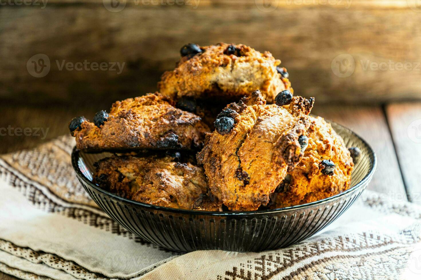 Homemade oatmeal cookies in a glass brown bowl on a kitchen napkin on a wooden table. photo