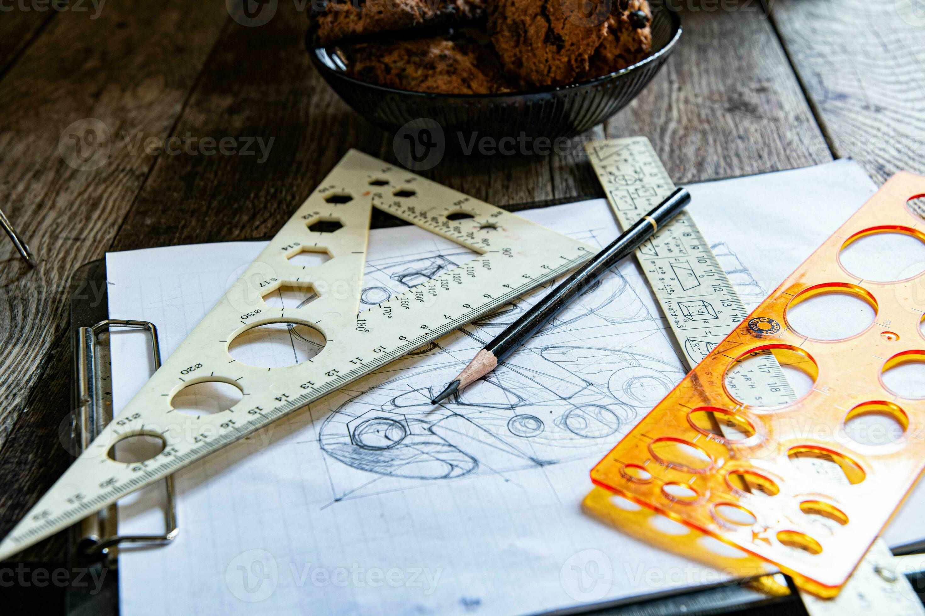 Pencil sketch, rulers, square and pencil on a wooden table. Attributes of an old designer