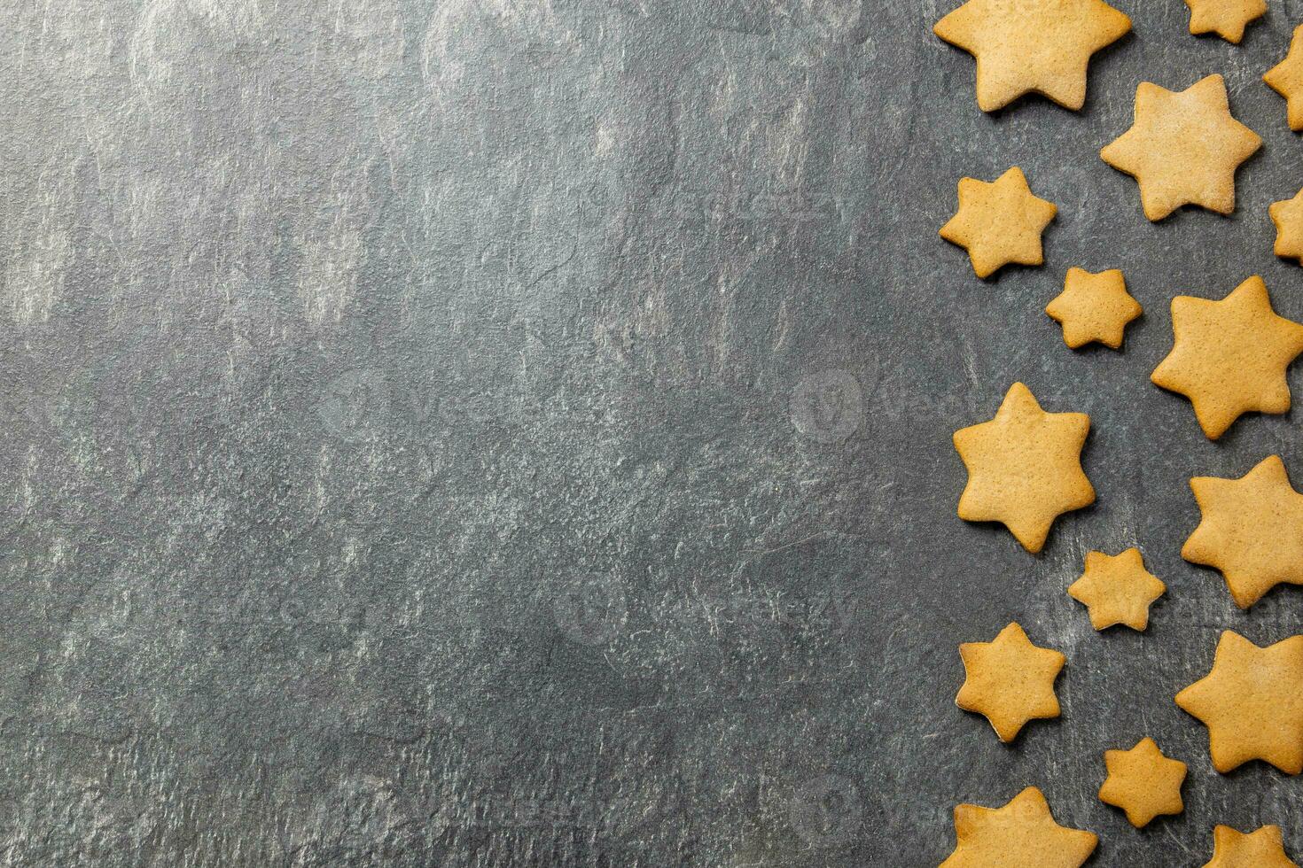 Christmas traditional gingerbread stars cookies on a dark stone background. Top view. Copy space. photo