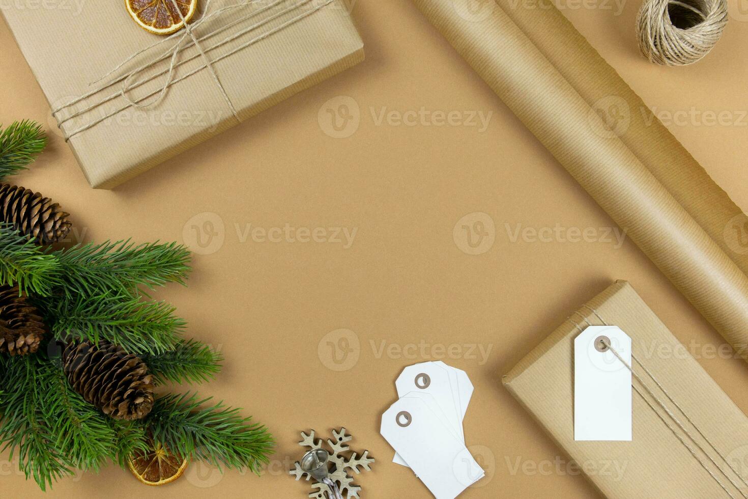 Christmas handmade gift boxes with label tag mockup, pine cones, fir tree branches and decoration on craft paper background. Festive styled composition. Top view. Copy space. photo