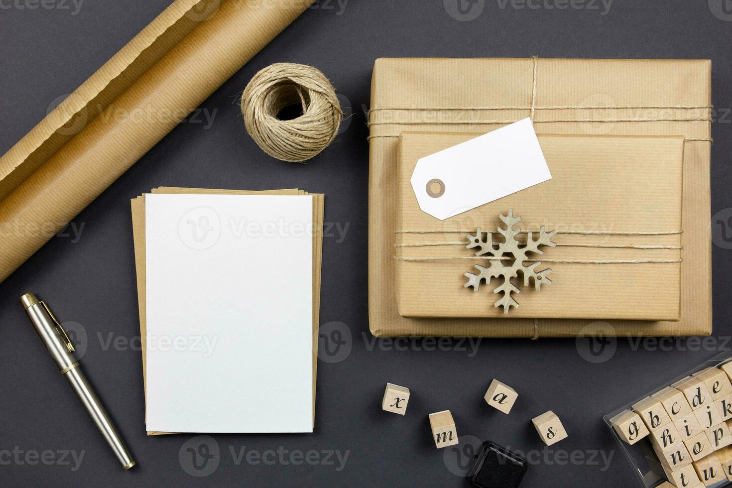 Christmas greeting card and envelope mockup with handmade gift boxes and decoration on dark background. Festive styled composition. Top view. Copy space. photo