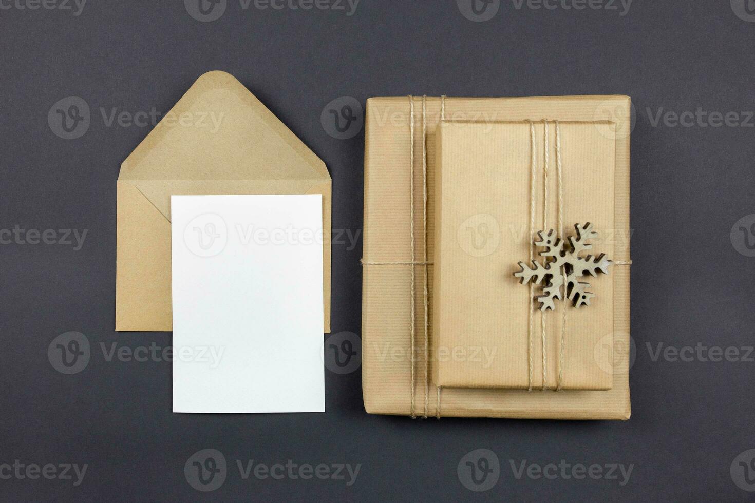 Christmas greeting card and envelope mockup with handmade gift box on dark background. Festive styled composition. Top view. Copy space. photo