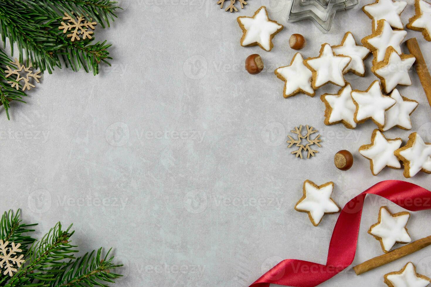 Christmas traditional German cookies, cinnamon stars with hazelnuts, decoration and tree branches on a light concrete background. Top view. Copy space. photo