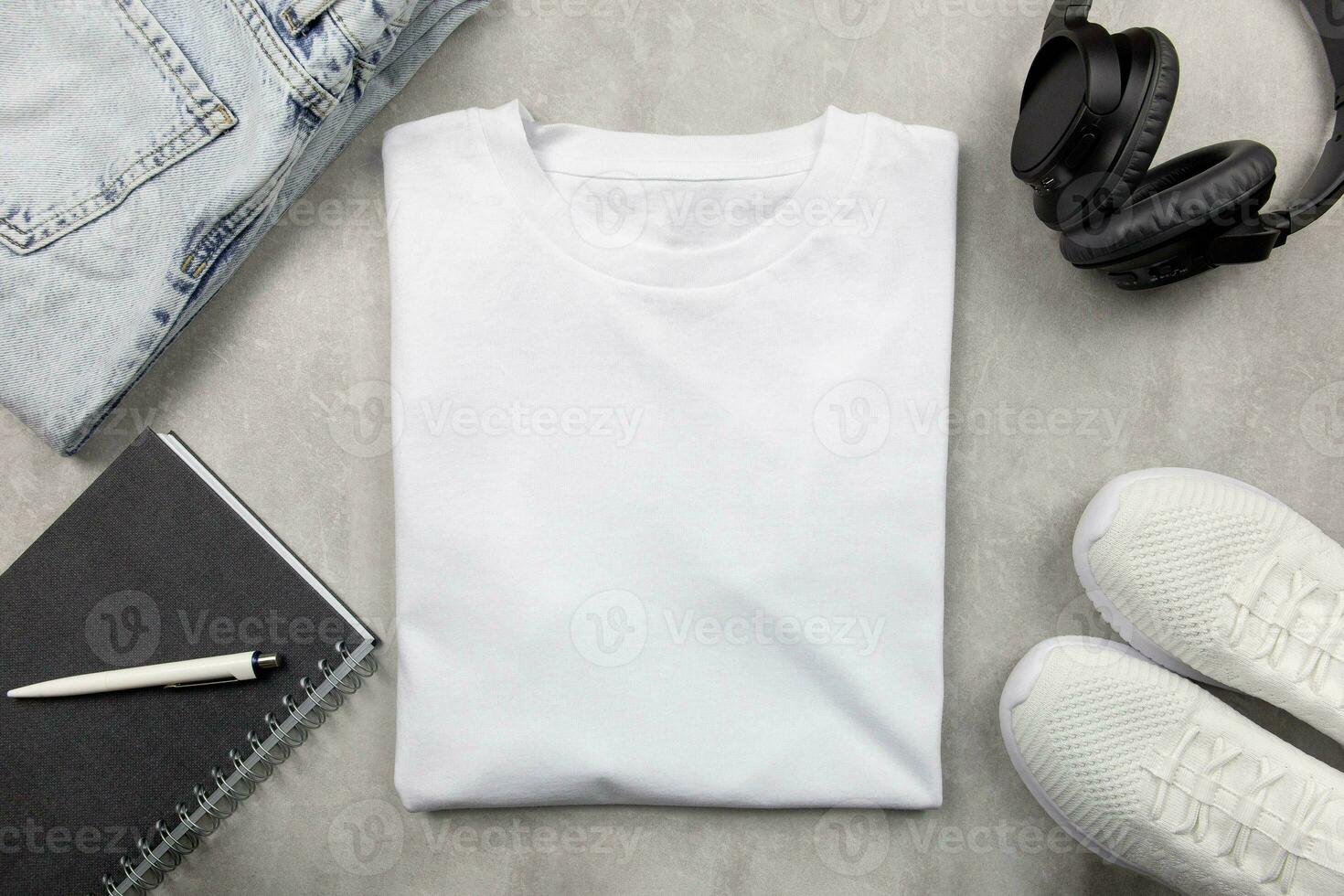 White womens cotton Tshirt mockup with jeans and sneakers, notebook and black headphones. Design t shirt template, print presentation mock up. Top view flat lay. Concrete stone background. photo