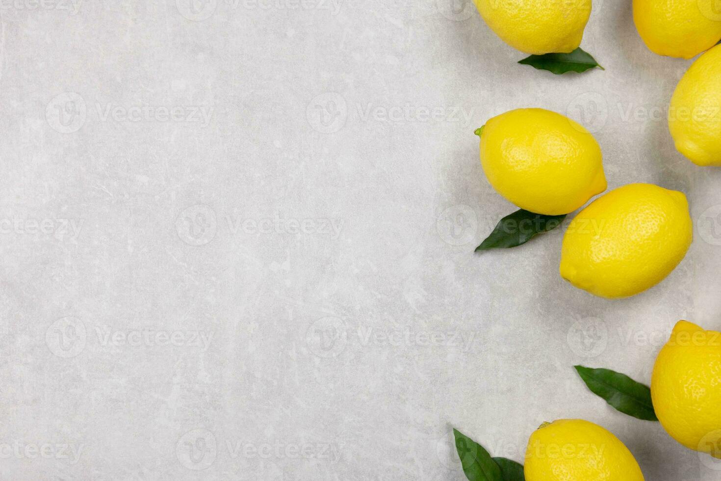 Fresh lemons with leaves on light gray concrete background. Vitamin C concept, immune defence. Top view. Copy space. photo
