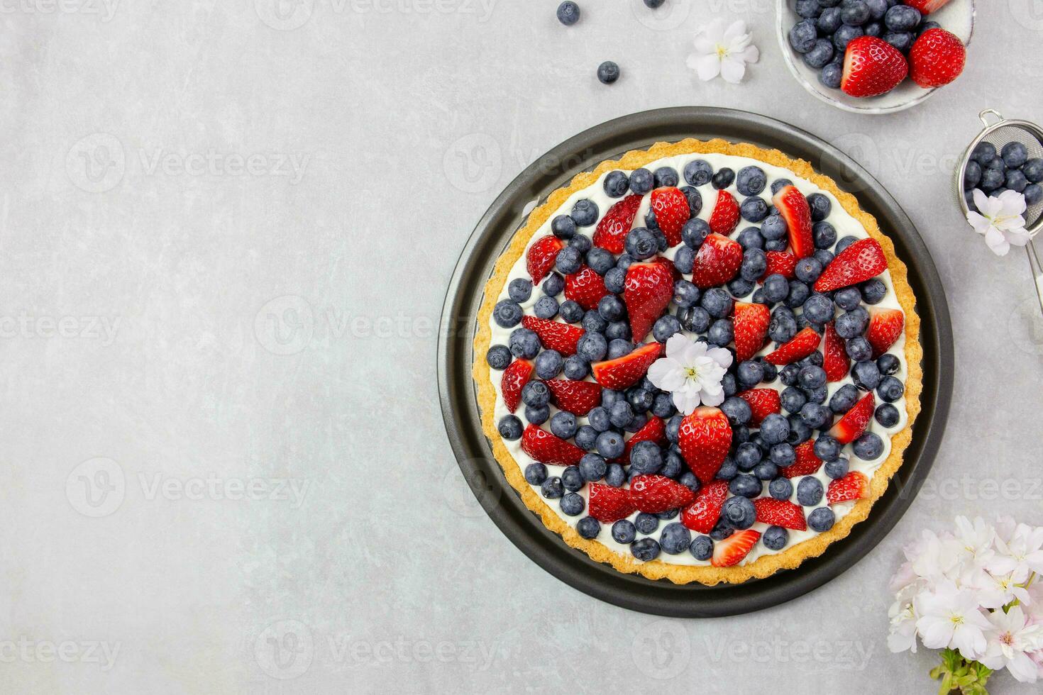 Delicious blueberry and strawberry tart with whipped cream and mascarpone on a light gray concrete background. Top view. Copy space. photo