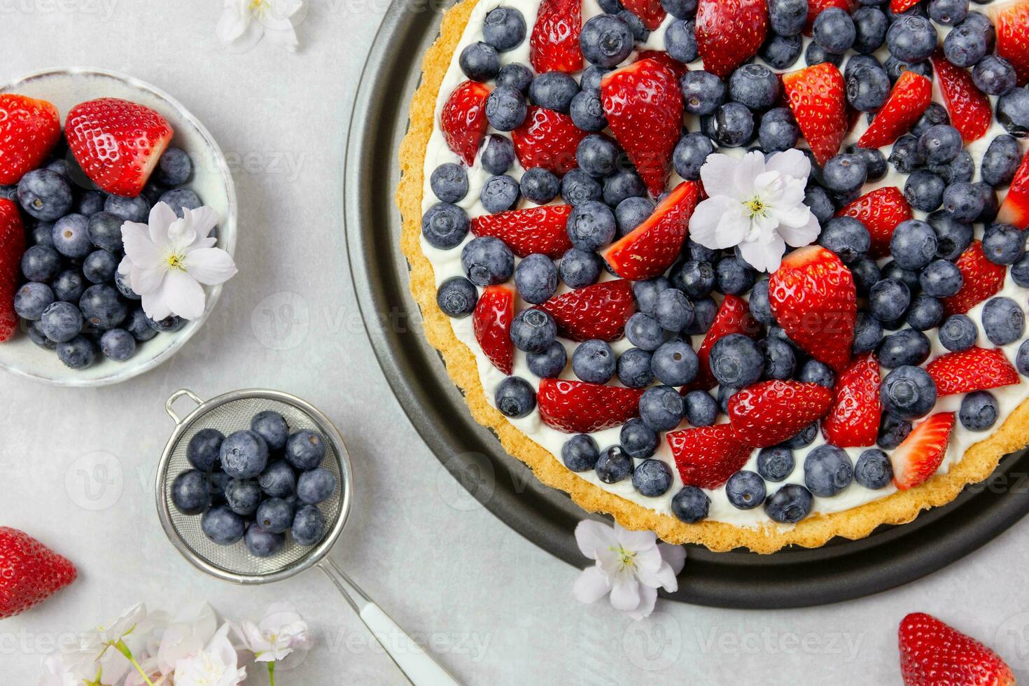 Delicious blueberry and strawberry tart with whipped cream and mascarpone on a light gray concrete background. Top view. Close up. photo