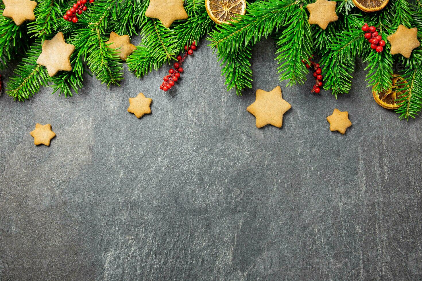 Christmas traditional gingerbread stars with decoration, spices and christmas tree branches on a dark stone background. Top view. Copy space. photo